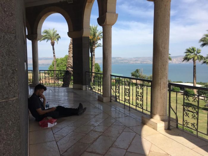 De franska pilgrimerna vilar under saligprisningarnas kyrkas portik på en kulle med utsikt över Galileiska sjön.