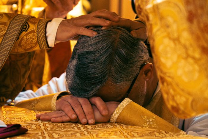 Fader Robert Pipta vilar sitt huvud på altaret vid sin biskopsvigning den 8 november 2023