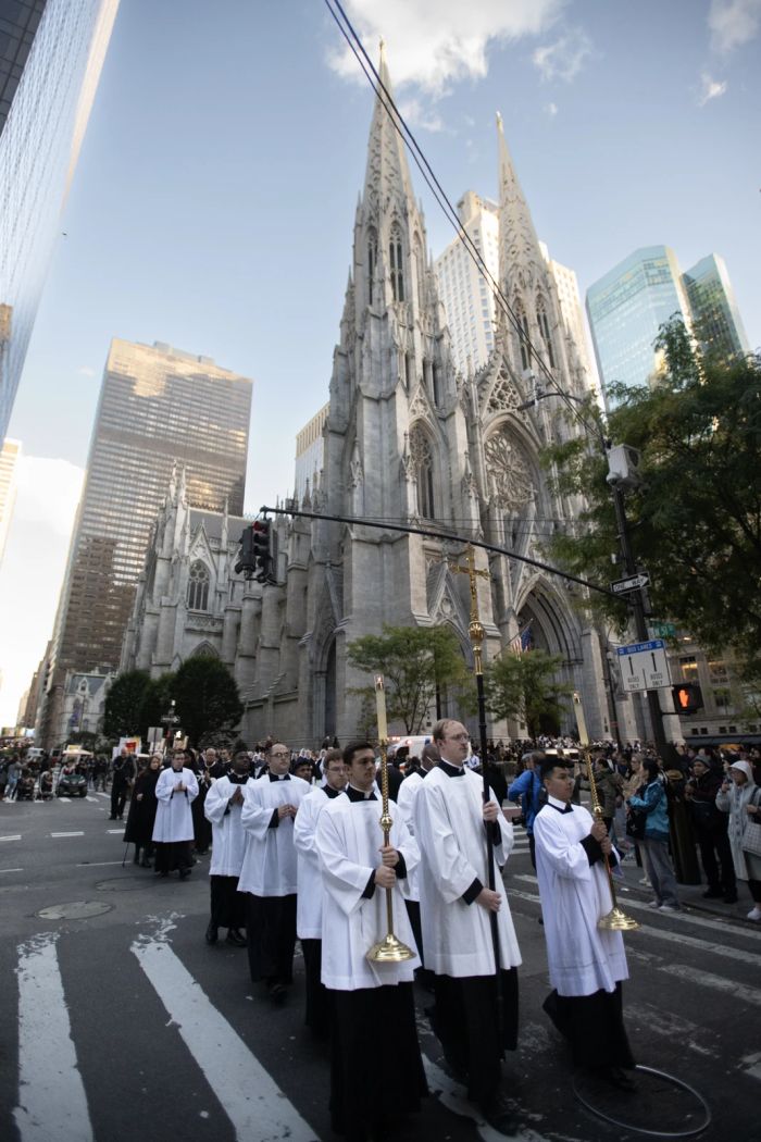 Seminarister som håller ett kors och ljus leder en eukaristisk procession ut ur St. Patrick's Cathedral i New York City den 15 oktober 2024.