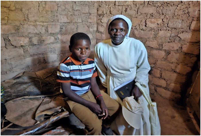 Syster till Mary, som är född i Tanzania, Asella Kokugonza Ernest, sitter bredvid Aneck i hans hem. Aneck hade just klarat provet och är nu student i Boystown.