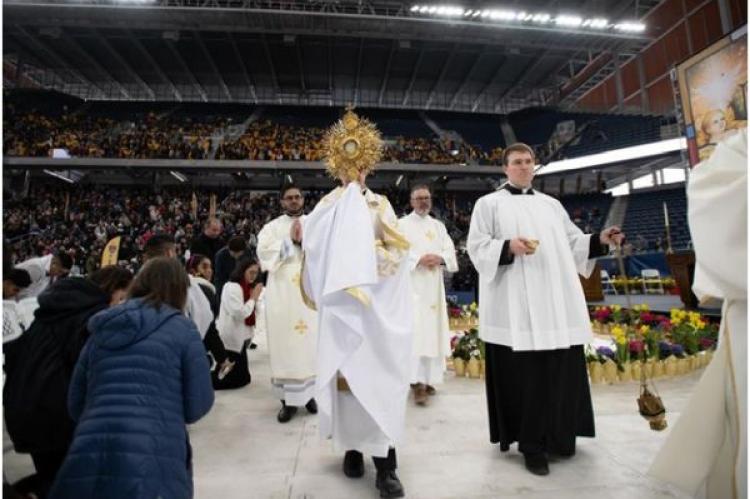 Biskop Robert Brennan leder en eukaristisk procession inne på ett fullsatt Louis Armstrong Stadium i Brooklyn