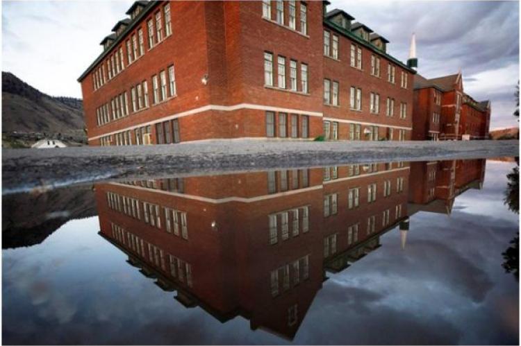 Den tidigare Kamloops Indian Residential School återspeglas i en vattenpöl i Kamloops, Kanada, den 1 september 2021.