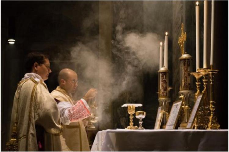 En katolsk präst firar den traditionella latinska mässan med en diakon och subdiakon och incenserar altaret i Sankt Pancratiuskyrkan i Rom