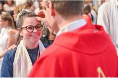 En ung kvinna mottar konfirmationens sakrament 2024 i Marie Upptagelsekyrkan i stiftet Lyon, Frankrike.